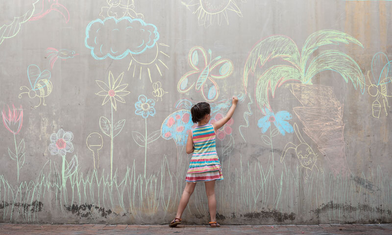 Mädchen malt mit Kreide an Wand