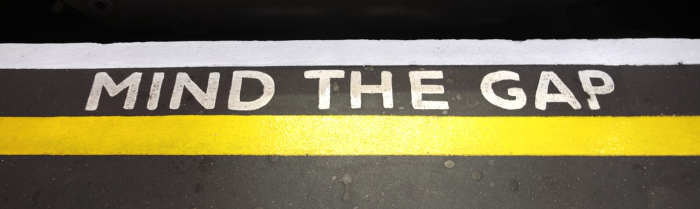 Fotografie einer U-Bahnsteigkante mit dem Text: Mind the Gap in Großbuchstaben