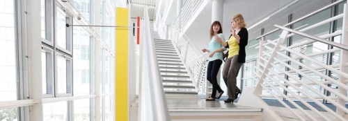 Zwei Personen unterhalten sich auf einer Treppe im FernUni Gebäude