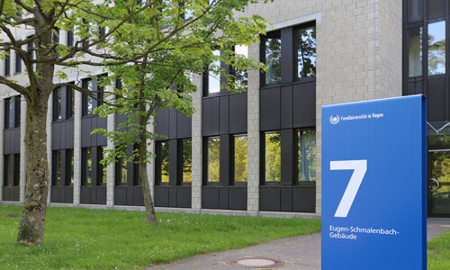 Foto des Schilds vom Eugen-Schmalenbach-Gebäudes, dahinter das Gebäude 