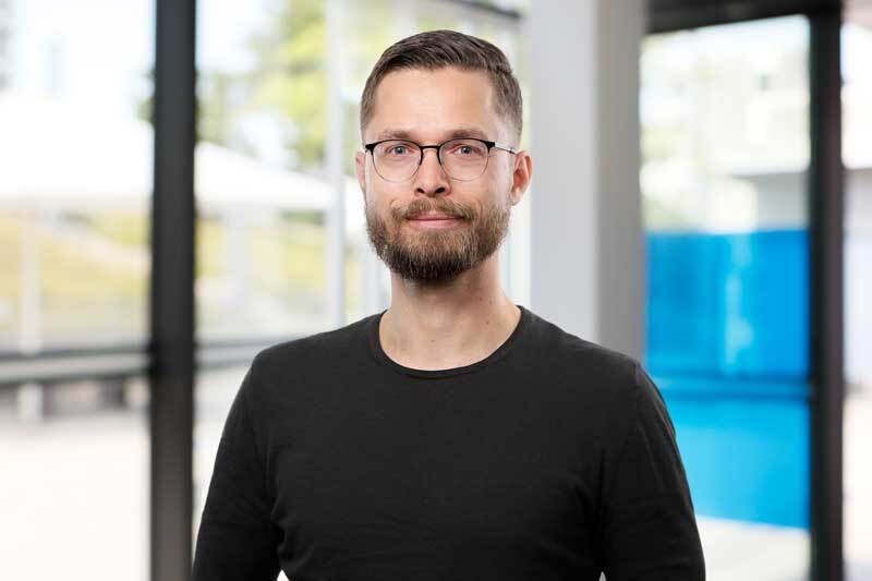 Ein Mann mit Brille steht in einem Foyer.