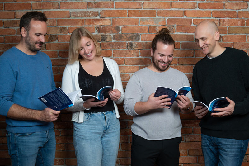 Drei Männer und eine Frau blättern in einem Buch