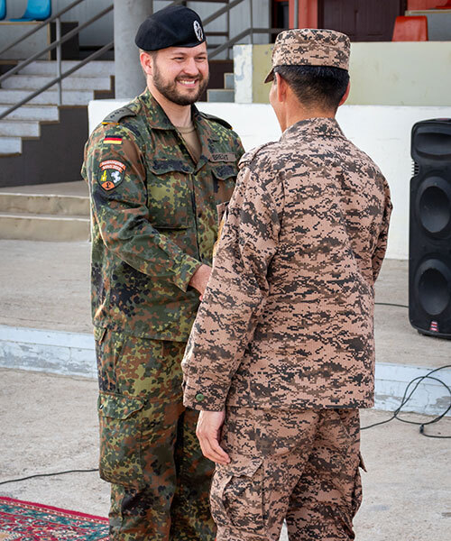 Zwei Männer in Uniform schütteln sich die Hände.