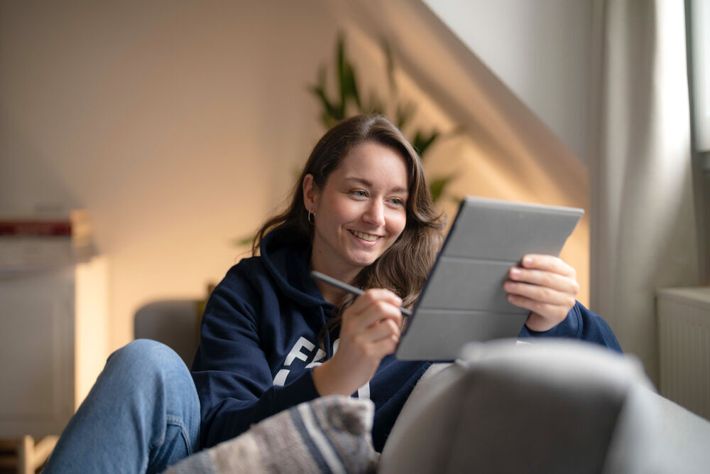 Smiling female student writing on a tablet PC with a stylus