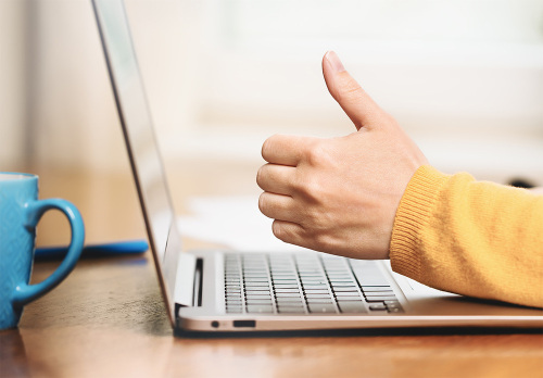 Ein Laptop und eine Hand, die einen Daumen nach oben streckt